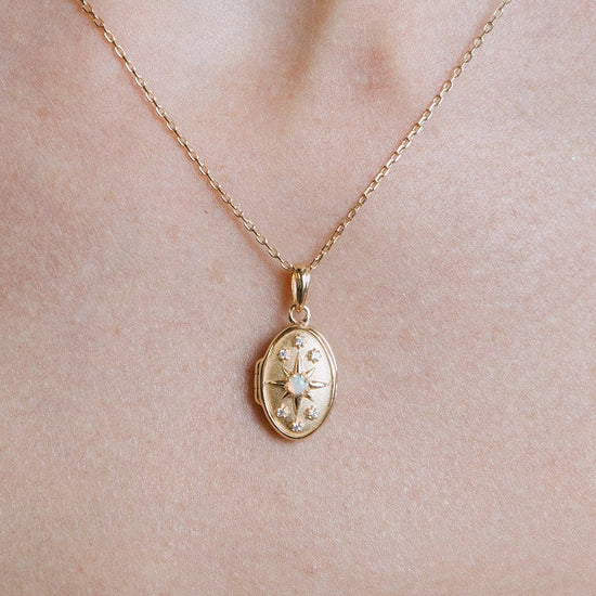Gold oval opal locket necklace with celestial compass star and moissanite details
