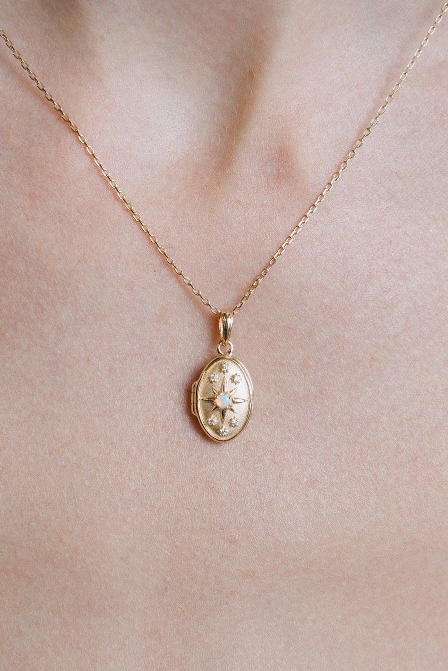 Gold oval opal locket necklace with celestial compass star and moissanite details