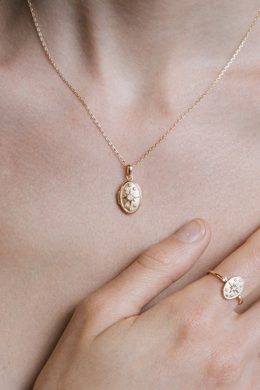 Gold oval opal locket necklace with celestial compass star and moissanite details