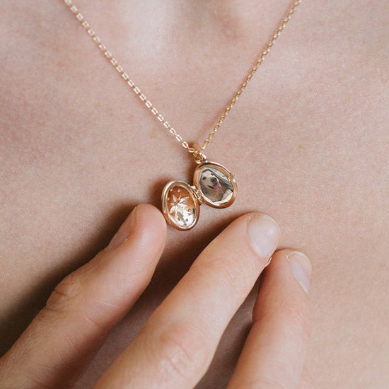 Gold oval opal locket necklace with celestial compass star and moissanite details