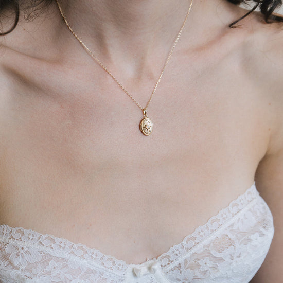 Gold oval opal locket necklace with celestial compass star and moissanite details