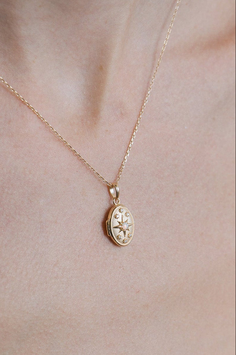 Gold oval opal locket necklace with celestial compass star and moissanite details