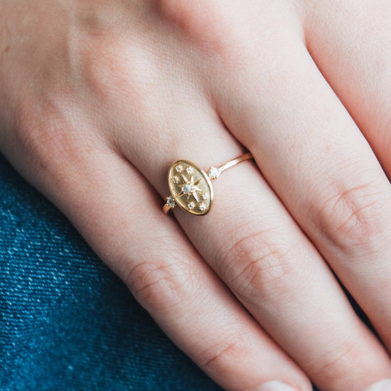 Dainty gold celestial compass ring with oval starburst design and sparkling accents