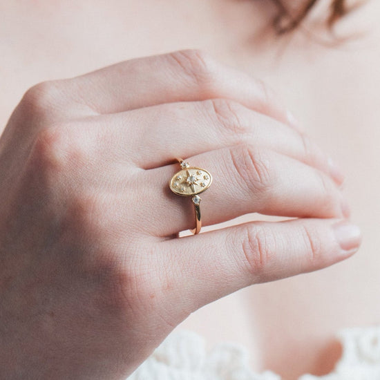 Dainty gold celestial compass ring with oval starburst design and sparkling accents