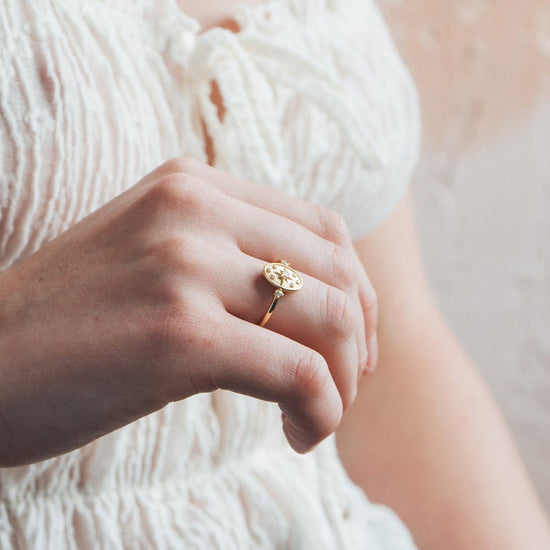 Dainty gold celestial compass ring with oval starburst design and sparkling accents