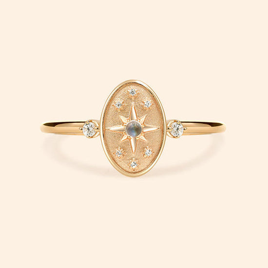 Dainty gold celestial compass ring with oval starburst design and sparkling accents