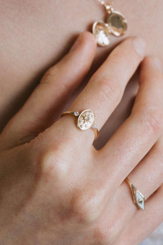 Dainty gold celestial compass ring with oval starburst design and sparkling accents
