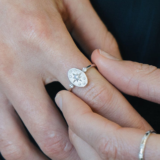 Dainty silver celestial compass ring with oval starburst design and sparkling accents