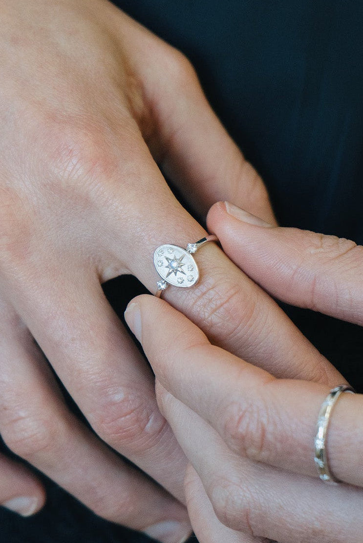 Dainty silver celestial compass ring with oval starburst design and sparkling accents