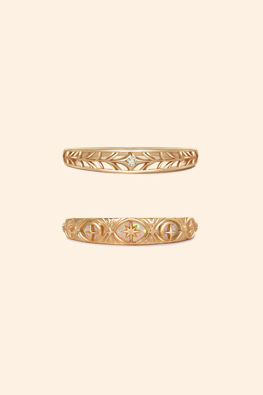 Two gold celestial stacking rings featuring iridescent opal star details and a center moissanite