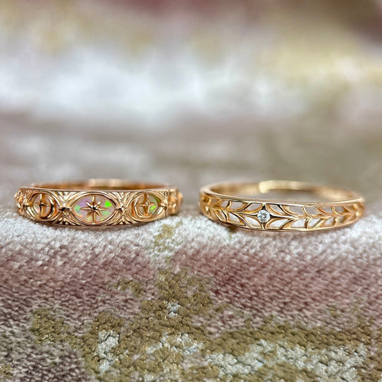 Two gold celestial stacking rings featuring iridescent opal star details and a center moissanite