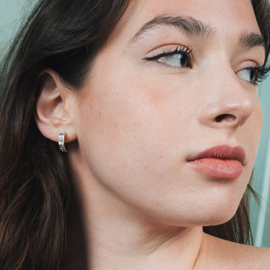 Silver solstice hoop earrings featuring fire opals and celestial starburst engravings by LIRAE.