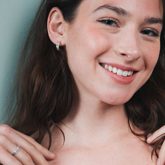 Silver solstice hoop earrings featuring fire opals and celestial starburst engravings by LIRAE.