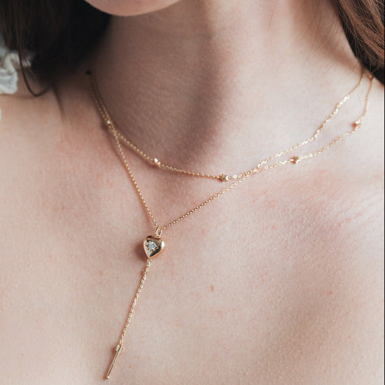 Gold heart arrow necklace with removable arrow and sparkling center moissanite stone