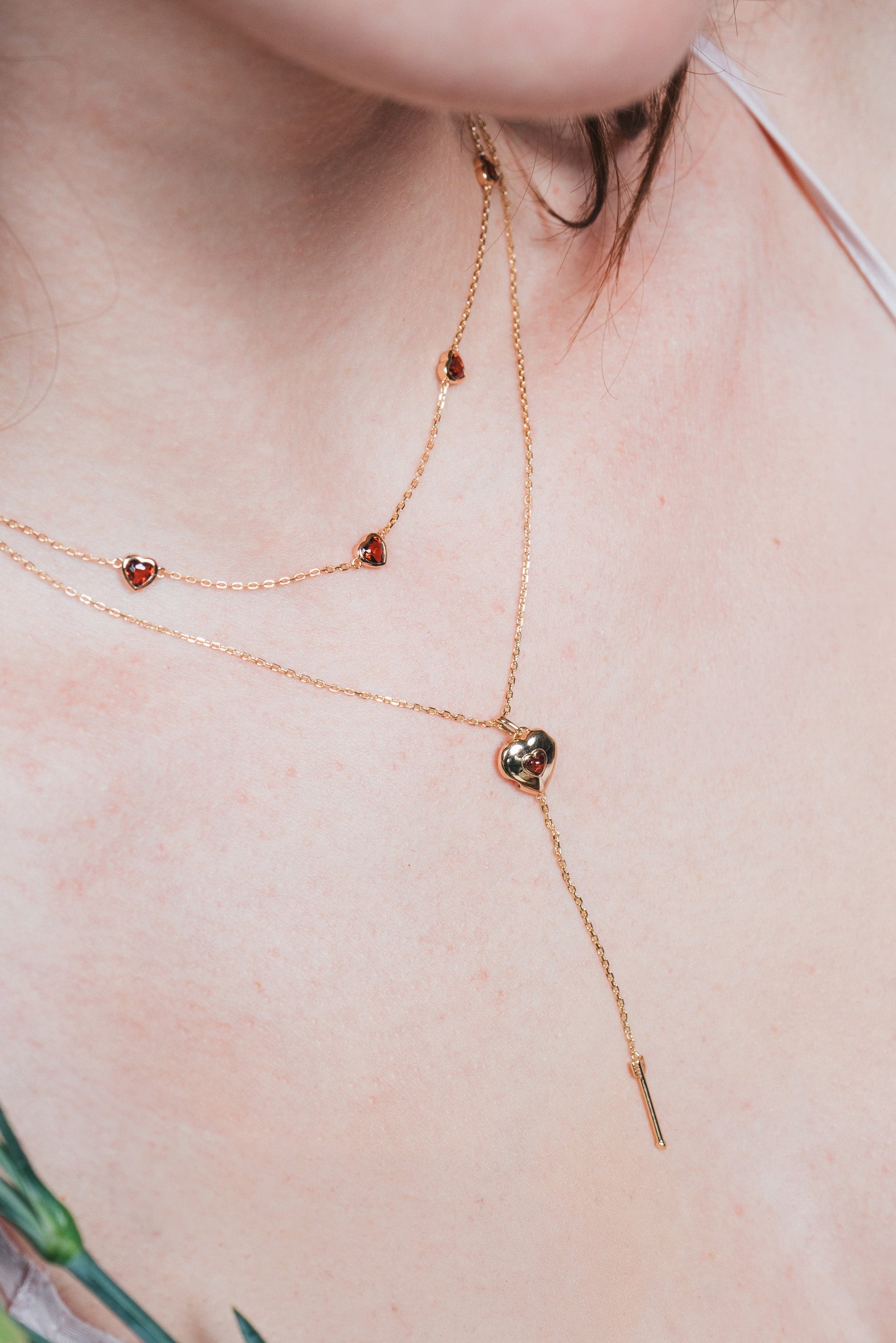 Gold heart charm necklace with removable arrow and red heart garnet center stone