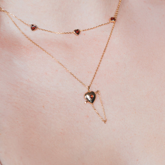 Gold heart charm necklace with removable arrow and red heart garnet center stone