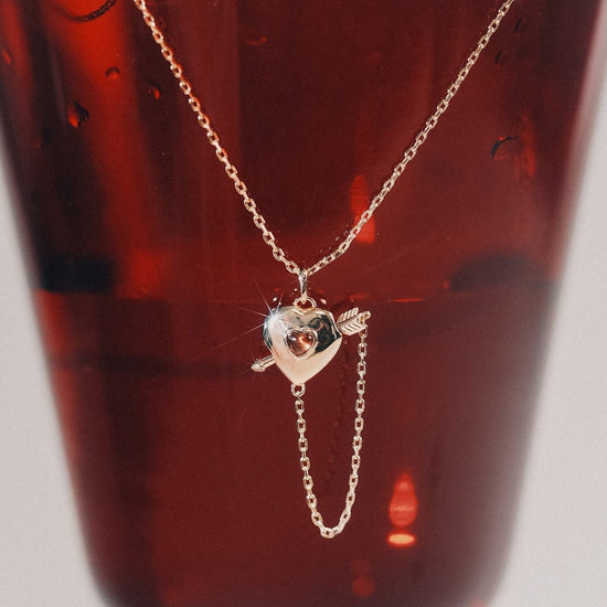Gold heart charm necklace with removable arrow and red heart garnet center stone