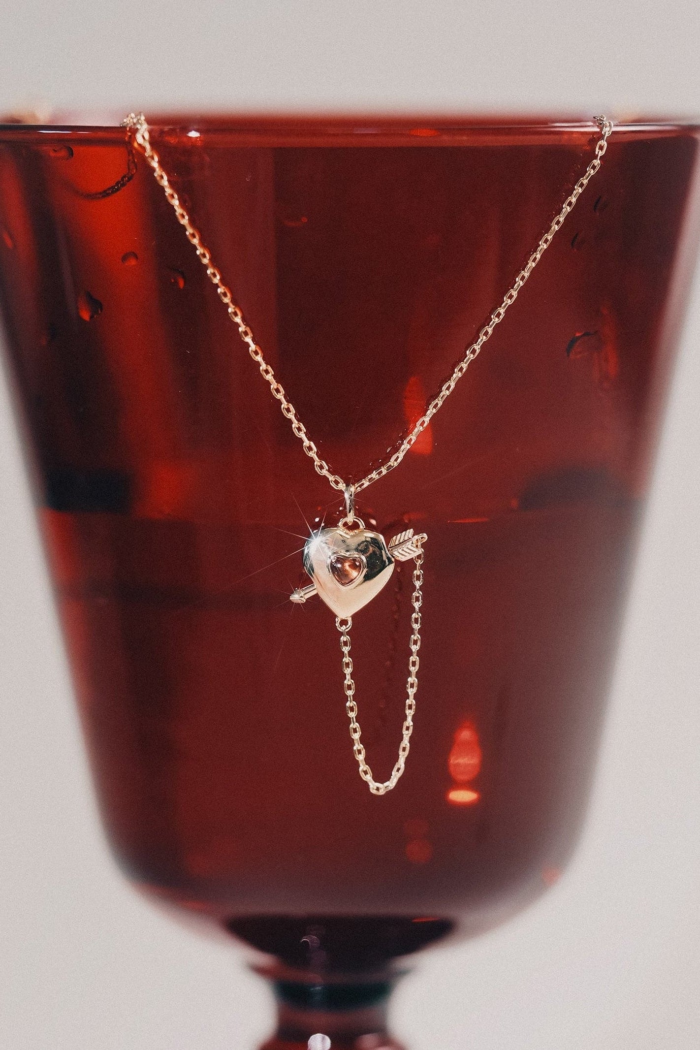 Gold heart charm necklace with removable arrow and red heart garnet center stone