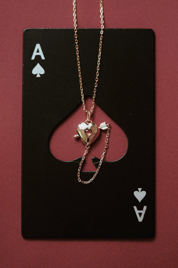 Gold heart charm necklace with removable arrow and red heart garnet center stone