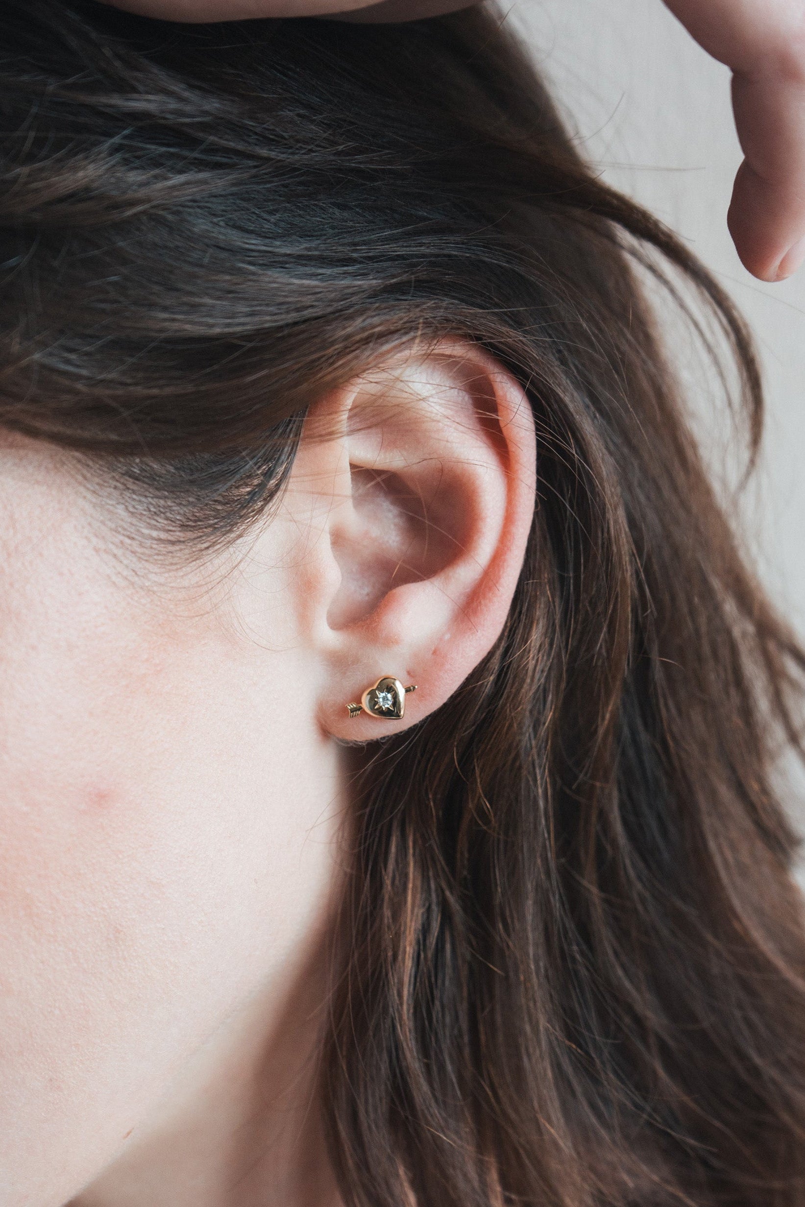 Dainty gold heart stud earrings with arrow details and sparkling center moissanite stones