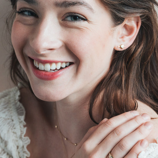 Dainty gold heart stud earrings with arrow details and sparkling center moissanite stones