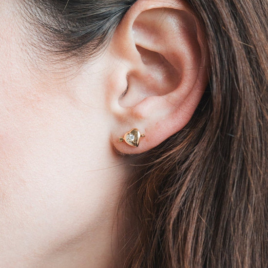 Dainty gold heart stud earrings with arrow details and sparkling center moissanite stones