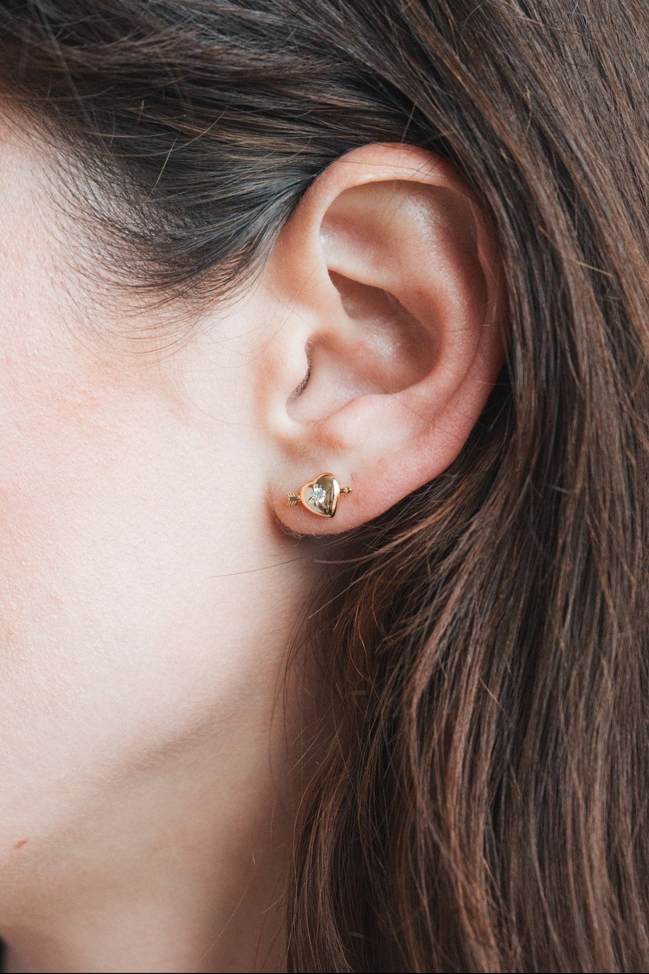 Dainty gold heart stud earrings with arrow details and sparkling center moissanite stones