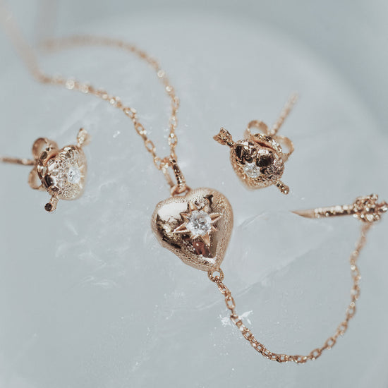Dainty gold heart stud earrings with arrow details and sparkling center moissanite stones