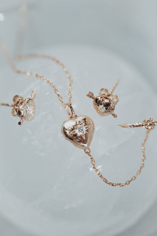 Dainty gold heart stud earrings with arrow details and sparkling center moissanite stones