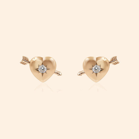 Dainty gold heart stud earrings with arrow details and sparkling center moissanite stones