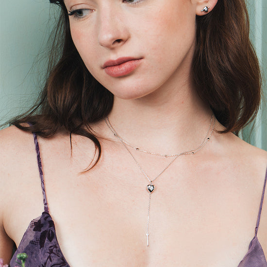 Dainty silver heart stud earrings with arrow details and sparkling center moissanite stones