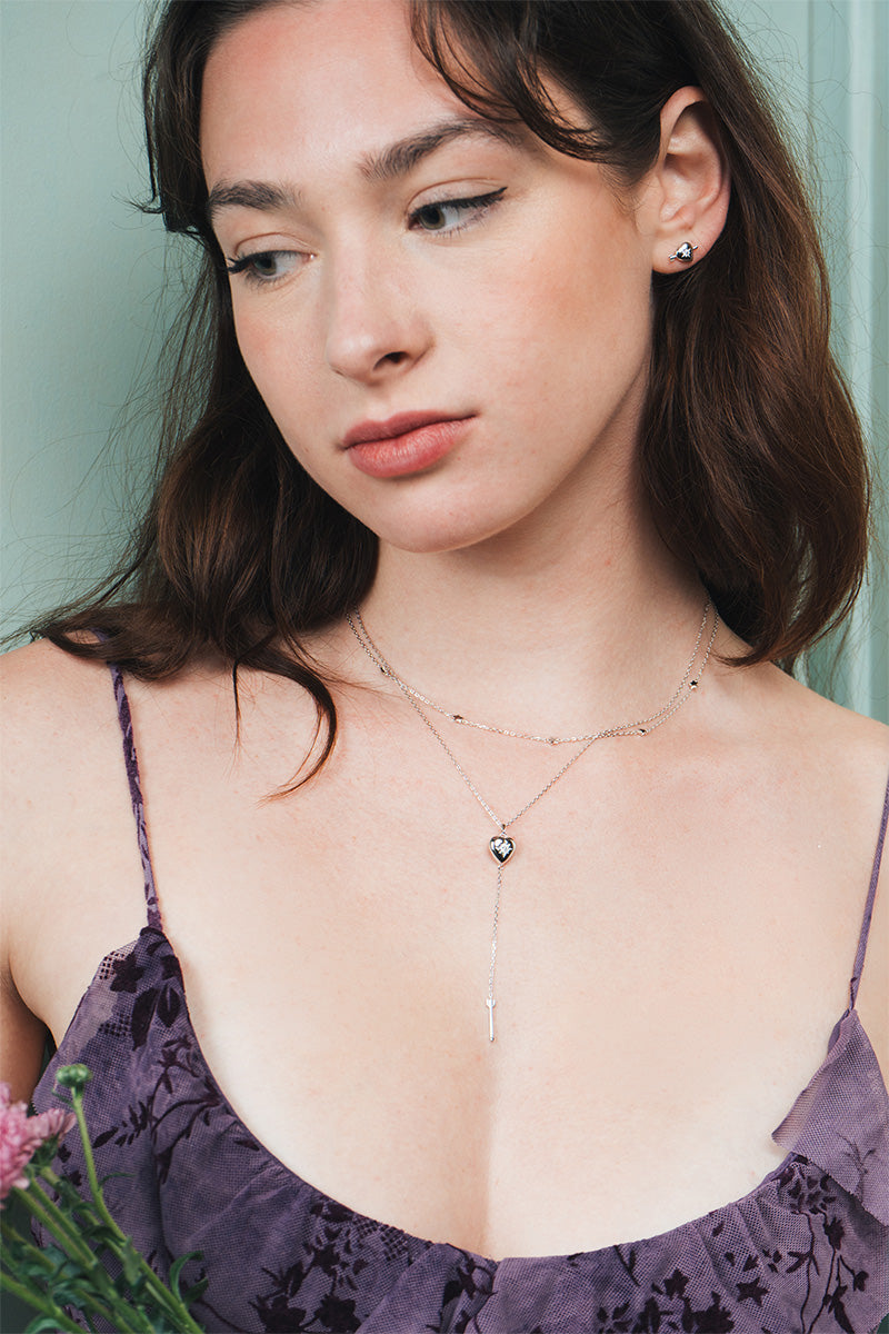 Dainty silver heart stud earrings with arrow details and sparkling center moissanite stones