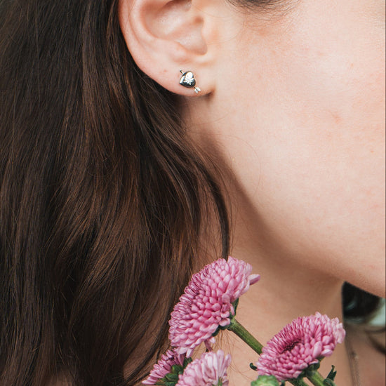 Dainty silver heart stud earrings with arrow details and sparkling center moissanite stones