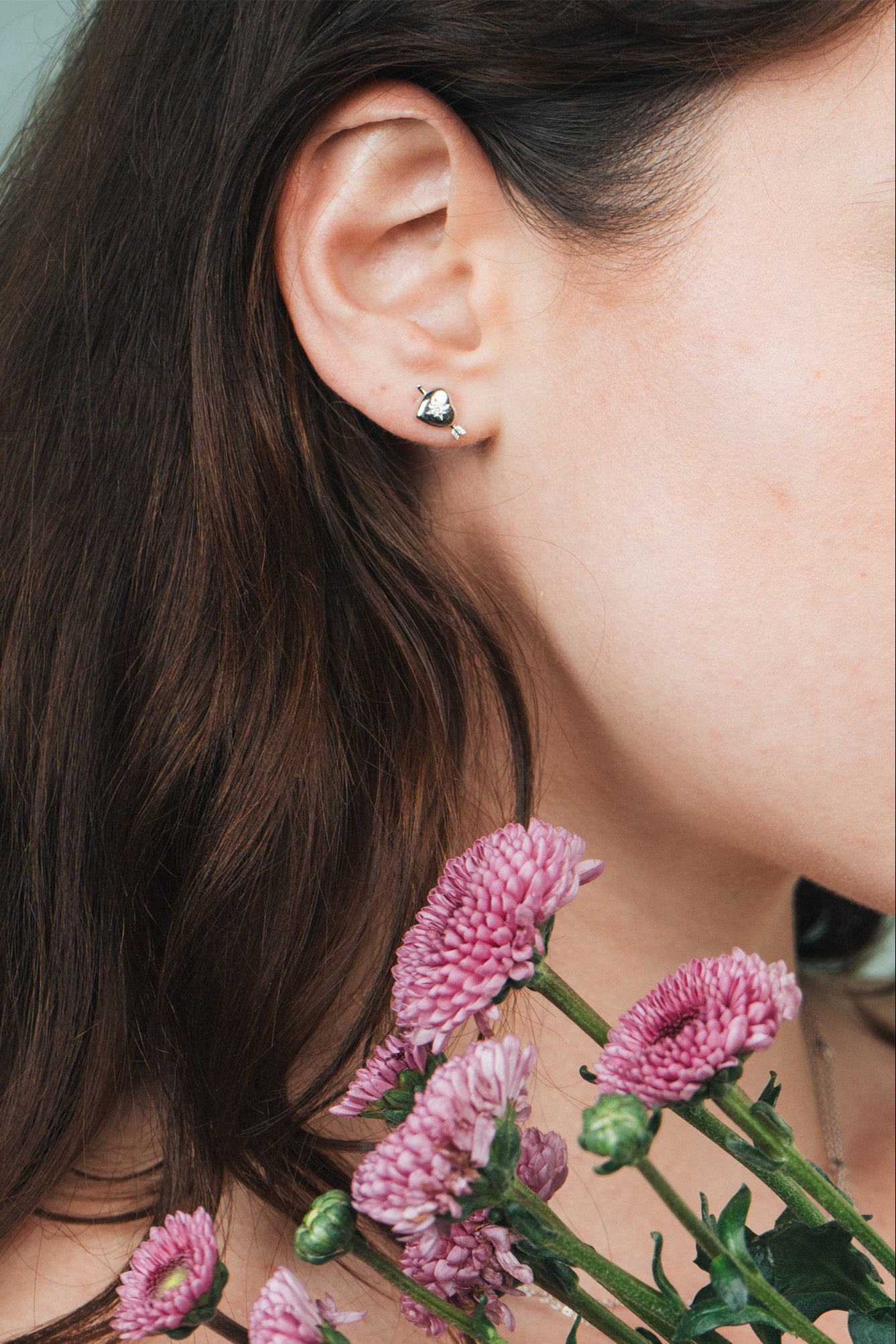 Dainty silver heart stud earrings with arrow details and sparkling center moissanite stones