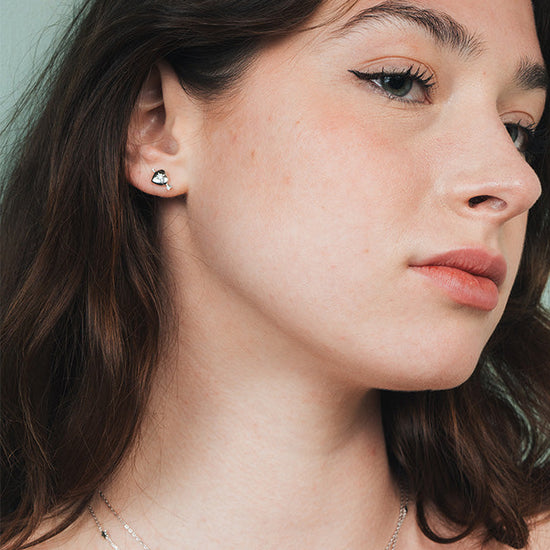 Dainty silver heart stud earrings with arrow details and sparkling center moissanite stones