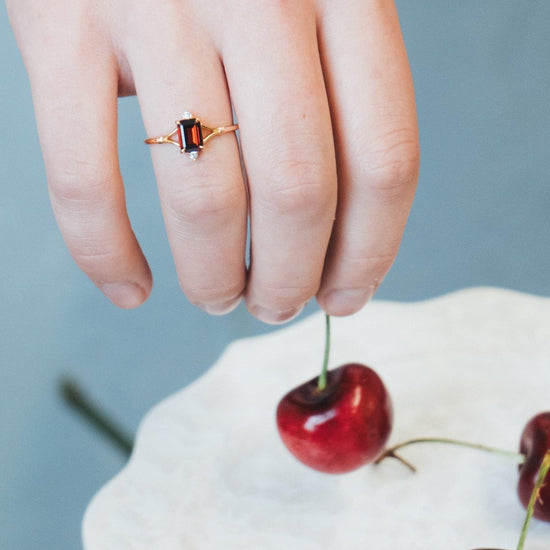 Dainty gold ring with emerald-cut garnet and sparkling moissanite accents