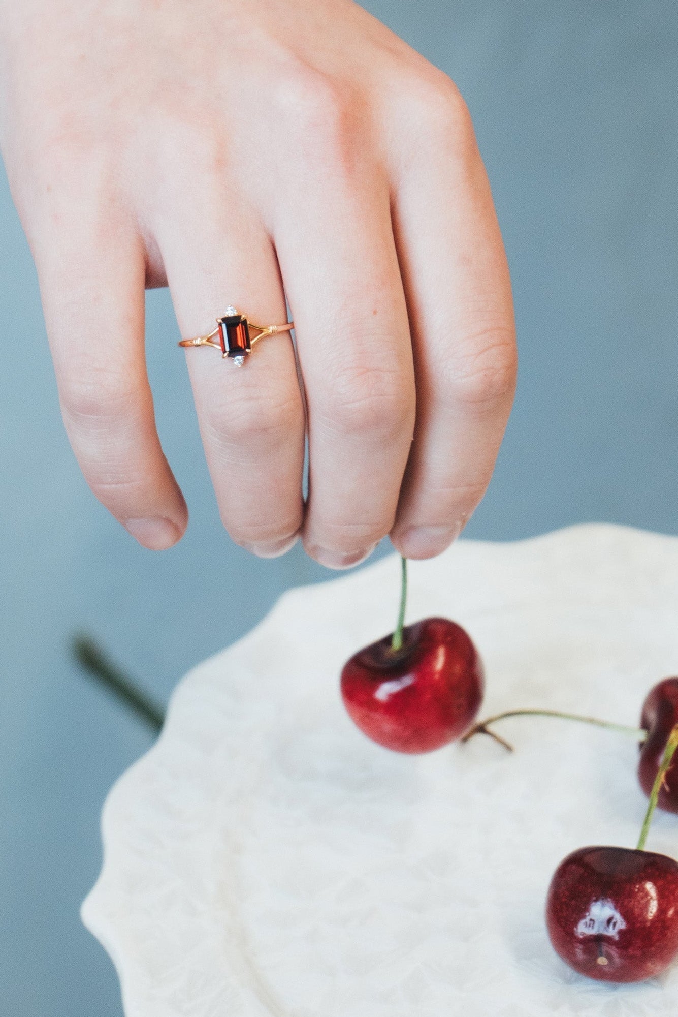 Dainty gold ring with emerald-cut garnet and sparkling moissanite accents