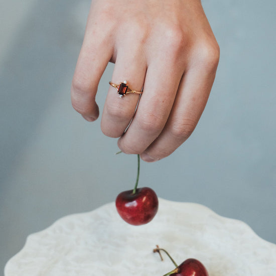 Dainty gold ring with emerald-cut garnet and sparkling moissanite accents