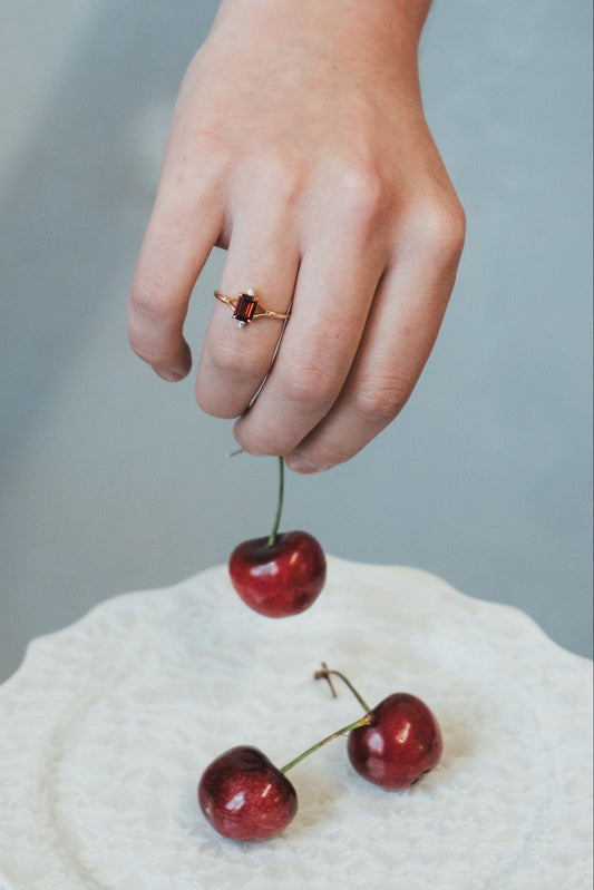 Dainty gold ring with emerald-cut garnet and sparkling moissanite accents
