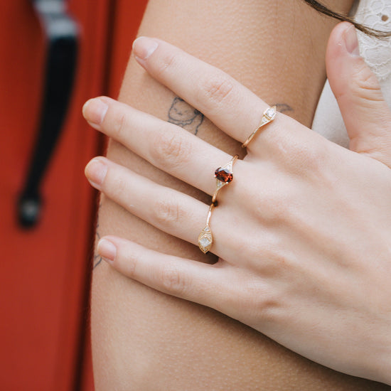 LIRAE vintage-style gold ring featuring an oval red garnet center stone and geometric rhombus accents with milgrain detailing, Art Deco stacking jewelry.