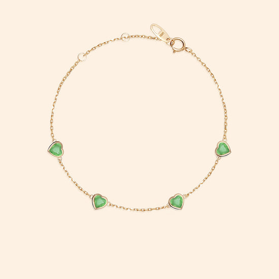 A delicate gold station necklace adorned with four petite, translucent heart-shaped green chalcedony gemstones.