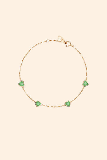 A delicate gold station necklace adorned with four petite, translucent heart-shaped green chalcedony gemstones.