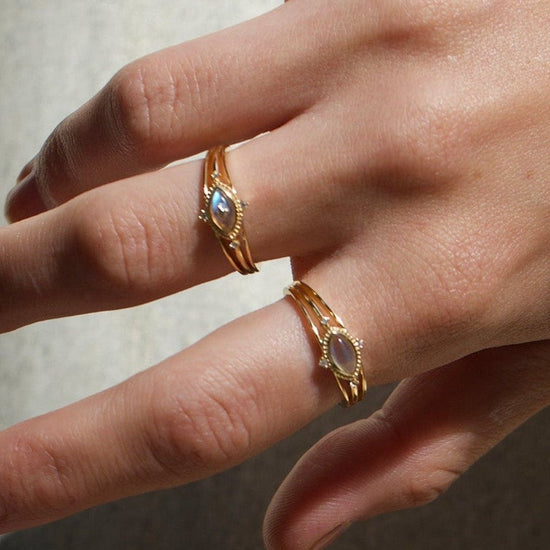 Marquise-cut flashy labradorite ring in 14k gold with a triple-band design and gold north star accent, ethereal celestial jewelry by LIRAE.