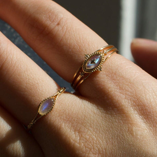 Marquise-cut flashy labradorite ring in 14k gold with a triple-band design and gold north star accent, ethereal celestial jewelry by LIRAE.