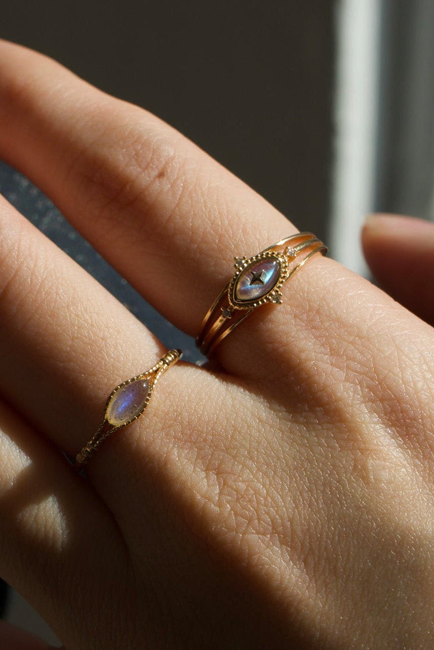 Marquise-cut flashy labradorite ring in 14k gold with a triple-band design and gold north star accent, ethereal celestial jewelry by LIRAE.