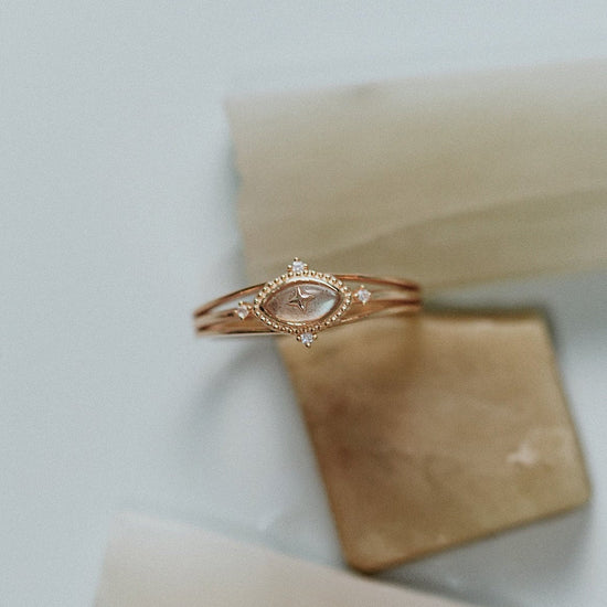Marquise-cut flashy labradorite ring in 14k gold with a triple-band design and gold north star accent, ethereal celestial jewelry by LIRAE.