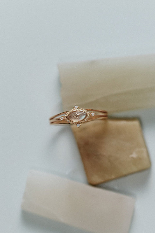 Marquise-cut flashy labradorite ring in 14k gold with a triple-band design and gold north star accent, ethereal celestial jewelry by LIRAE.