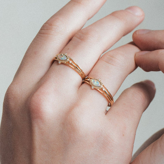 Marquise-cut iridescent opal ring in gold with a triple-band design and north star accents, ethereal celestial jewelry by LIRAE.