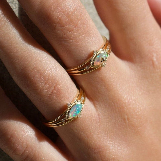 Marquise-cut iridescent opal ring in 14k gold with a triple-band design and north star accents, ethereal celestial jewelry by LIRAE.