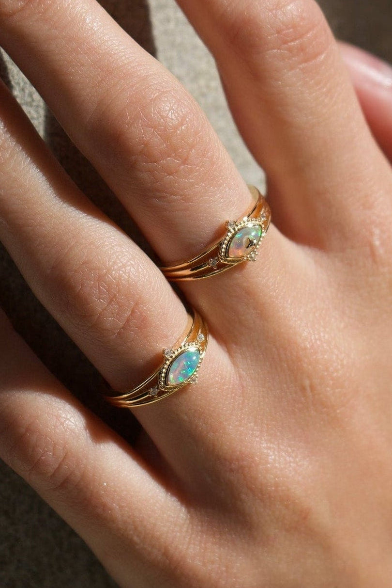 Marquise-cut iridescent opal ring in 14k gold with a triple-band design and north star accents, ethereal celestial jewelry by LIRAE.